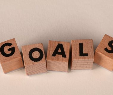 Aligned wooden blocks spelling 'Goals' symbolize target achievement and ambition.
